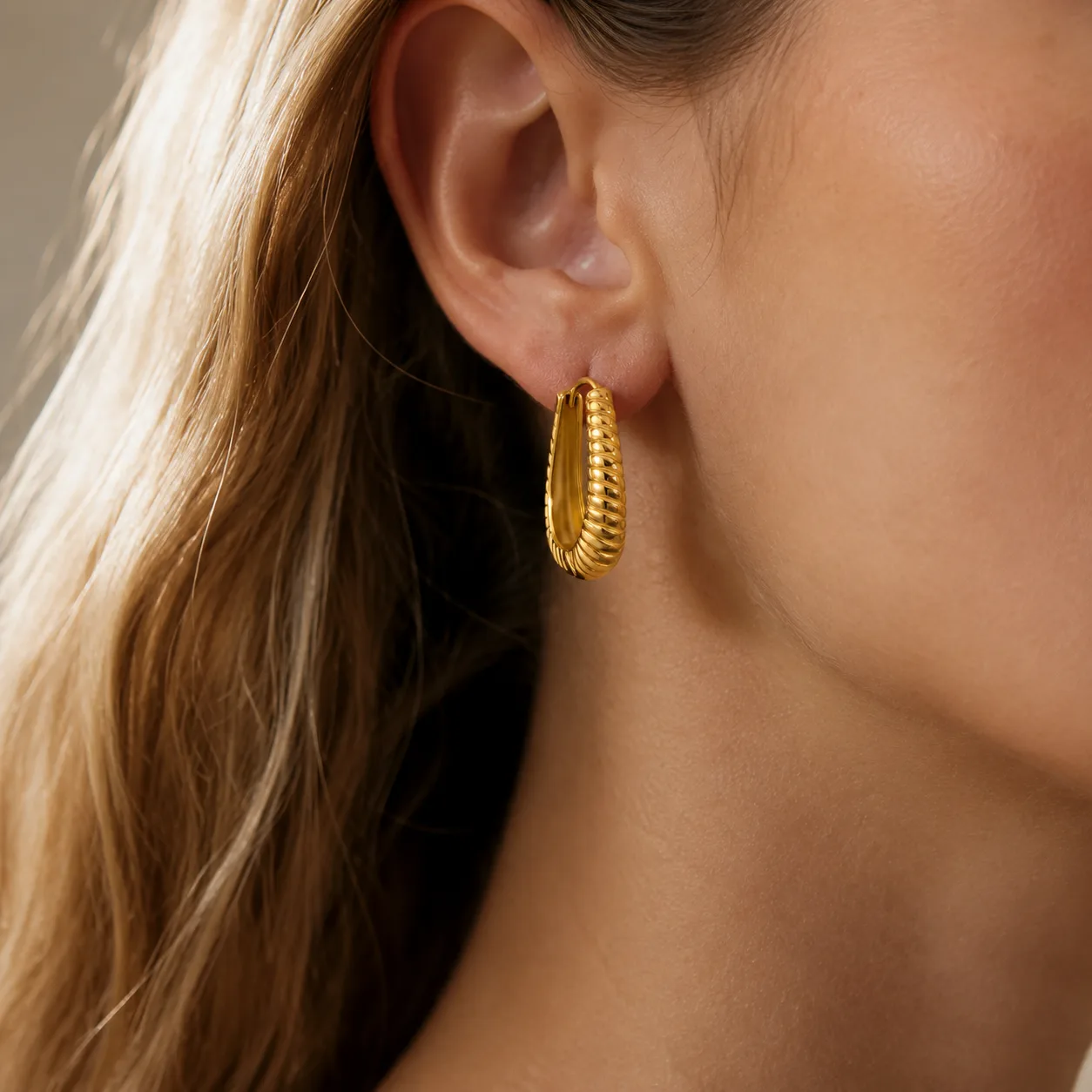 EH05004 gold-tone ribbed oval earring worn on the ear; styling reference